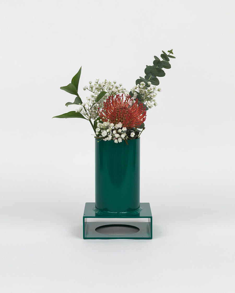 a green vase filled with red and white flowers 