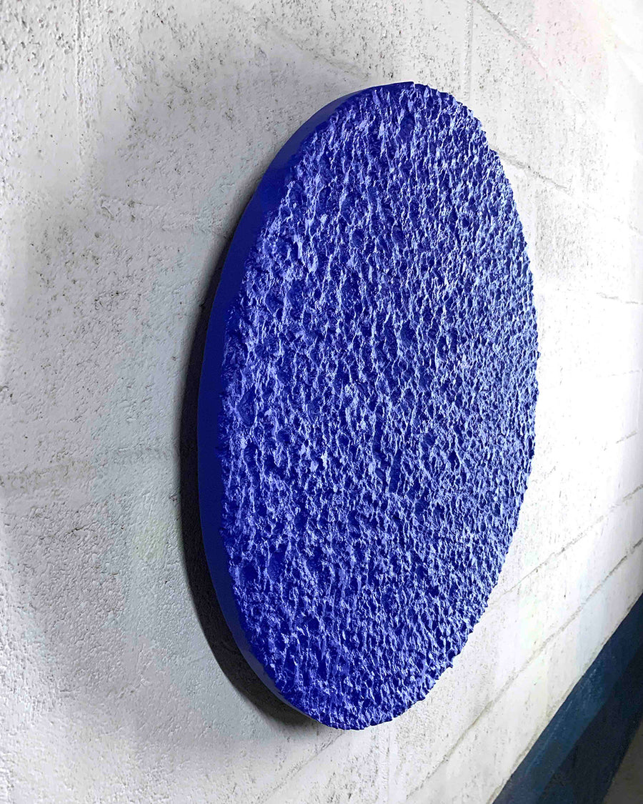a blue blue and white frisbee sitting on a white surface 